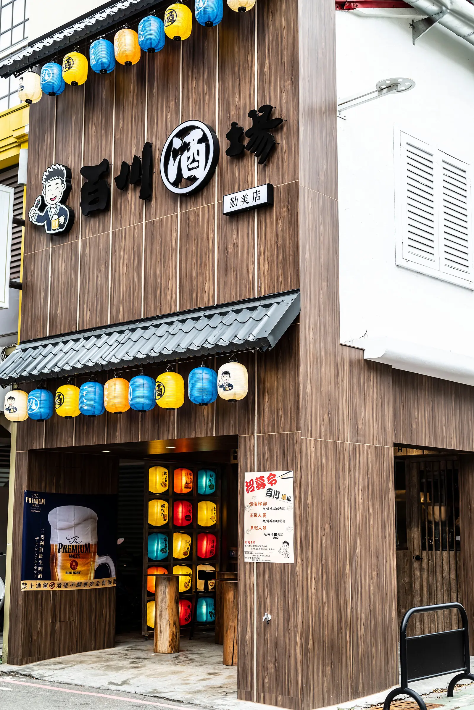 台中居酒屋外觀，深色木紋立面、日式瓦簷與整排燈籠